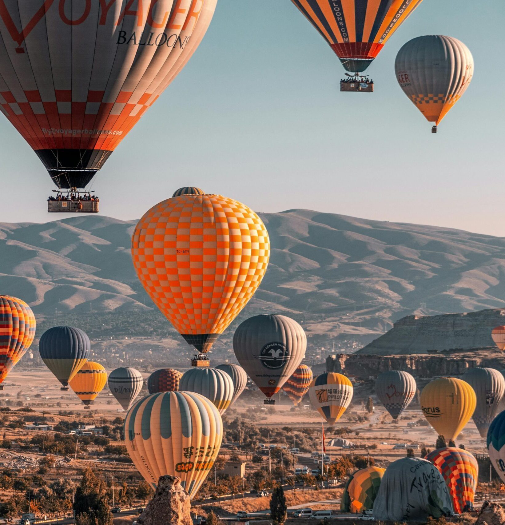 Colorful hot air balloons soaring over Cappadocia's unique landscape in Türkiye.