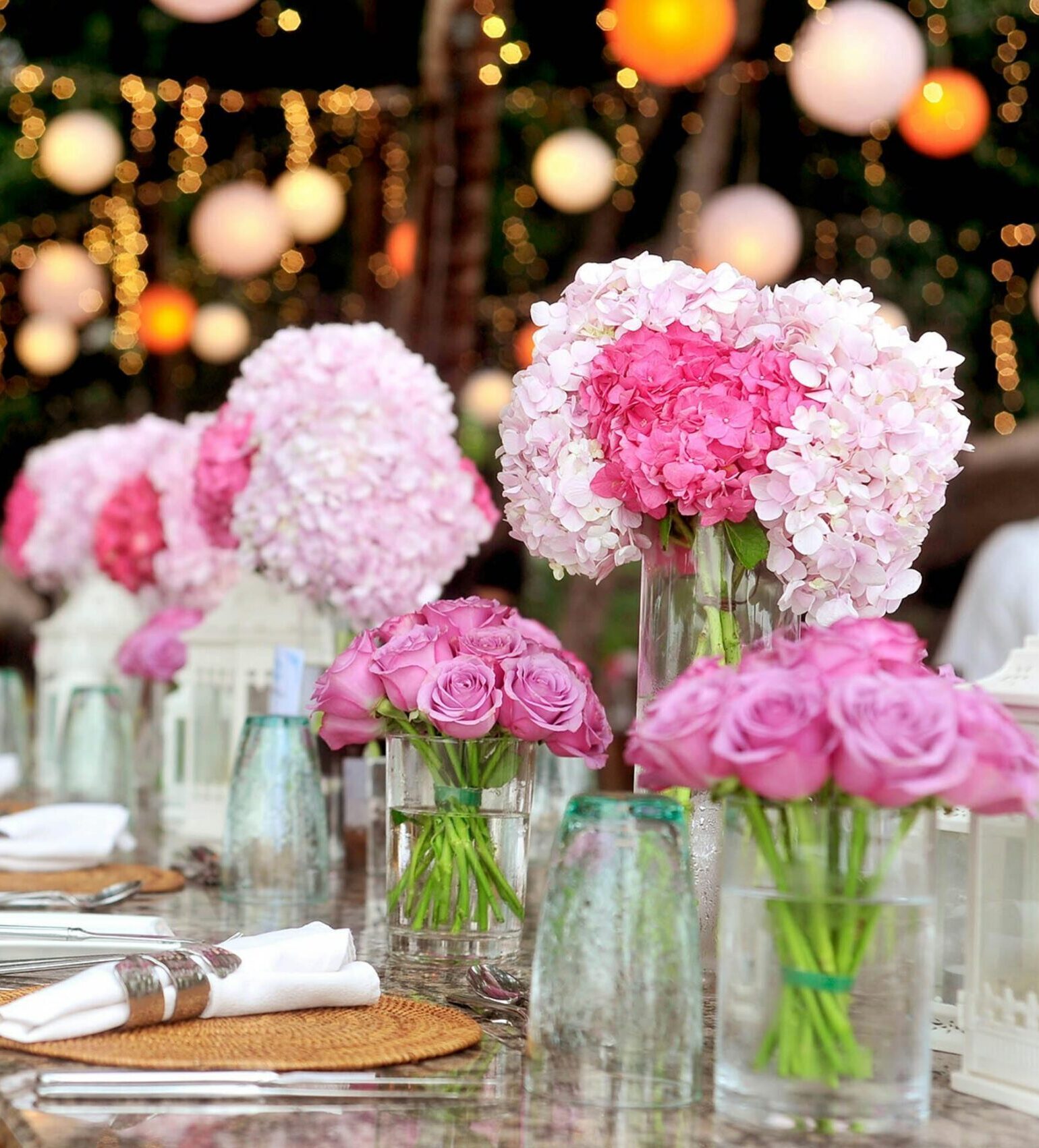 Elegant outdoor wedding setup featuring pink floral arrangements and soft lighting.