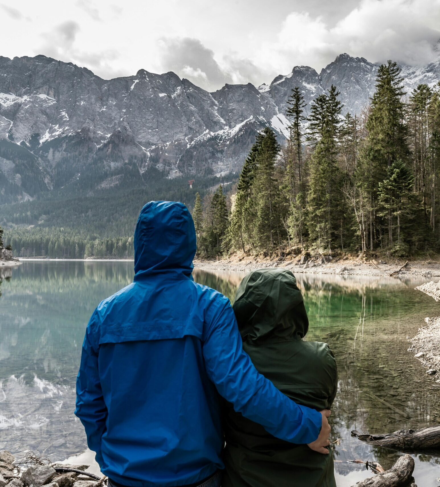 Romantic couple hugging and admiring the view of a mountain lake in Grainau, Germany.